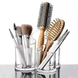 Makeup brushes and hair brushes organized in clear glass holders on a vanity table